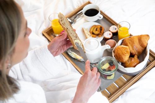 Una mujer comiendo una bandeja de desayuno en una cama. en Hotel Etats Unis Opera, en París