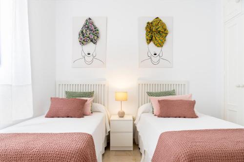 twee bedden in een slaapkamer met roze en wit bij Magno Apartments Alfarería - Private Parking included in Sevilla