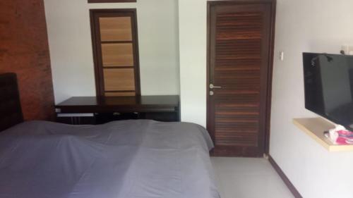 1 dormitorio con 1 cama, TV y escritorio en Villa Adhi Rajasa, en Penebel