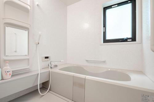 a white bathroom with a tub and a window at S-villa Nasu 9th in Nasu