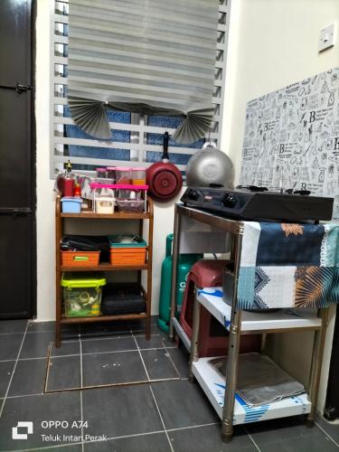a room with a table and some shelves at Homestay Kak Ninie in Teluk Intan