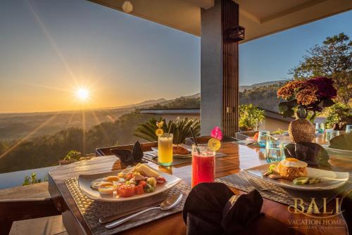 a table with food and drinks on a balcony with the sunset at THE most luxury 5BR villa in Lovina! Stunning Outlook! in Lovina