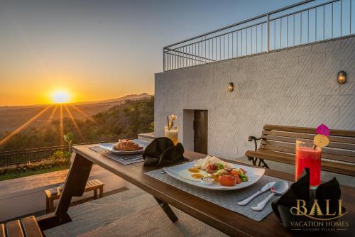 a table with a plate of food on a balcony with the sunset at THE most luxury 5BR villa in Lovina! Stunning Outlook! in Lovina