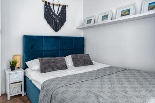 een bed met een blauw hoofdeinde in een slaapkamer bij Apartament PRIMAVERA z miejscem parkingowym in Toruń