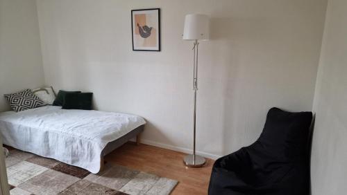 ein Schlafzimmer mit einem Bett, einer Lampe und einem Stuhl in der Unterkunft Halmstad/Oskarström in Oskarström