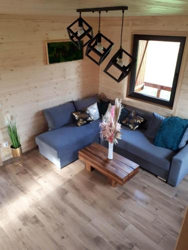 a living room with a blue couch and a table at Domki OstoYa Bieszczady/Solina in Myczkowce