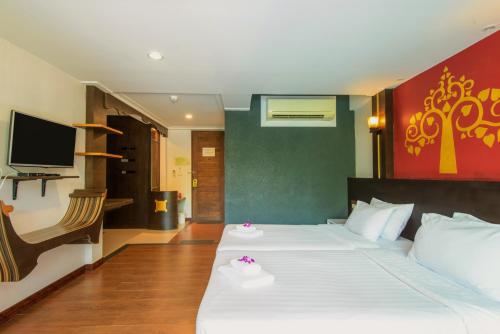 a bedroom with a large white bed with a tv at Baan Grood Arcadia Resort & Spa in Ban Krut