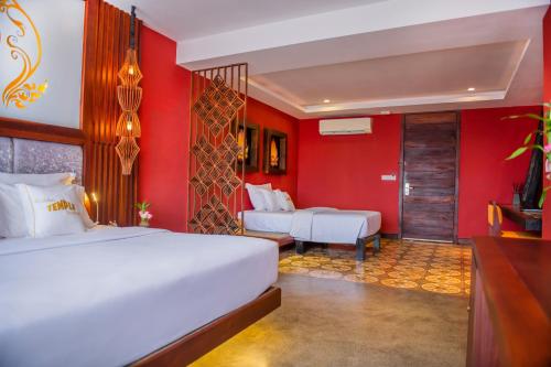 a bedroom with two beds and a red wall at Golden Temple Boutique in Siem Reap