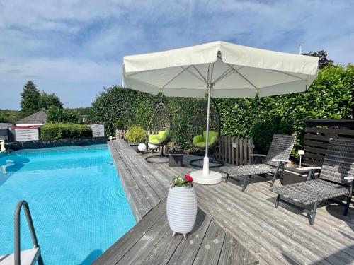 eine Terrasse mit einem Sonnenschirm und einem Pool in der Unterkunft Schöne helle Ferienwohnung 35606 Solms Lahn Küche separat in Braunfels
