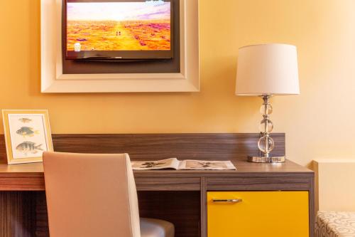 a desk with a lamp and a television on a wall at Park Hotel Residence in Orbetello