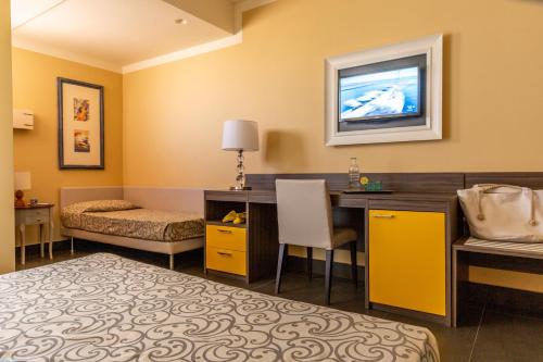 a hotel room with a bed and a desk and a tv at Park Hotel Residence in Orbetello