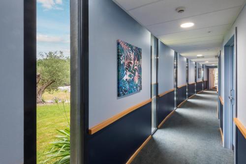 un pasillo en una escuela con paredes azules y una ventana en Best Western Plus Hotel De La Regate-Erdre, en Nantes