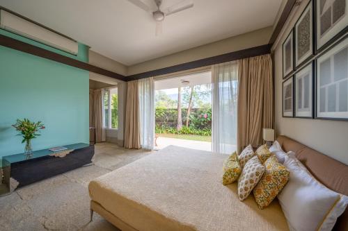ein Schlafzimmer mit einem Bett und einem großen Fenster in der Unterkunft LohonoStays Villa Amber in Alibag