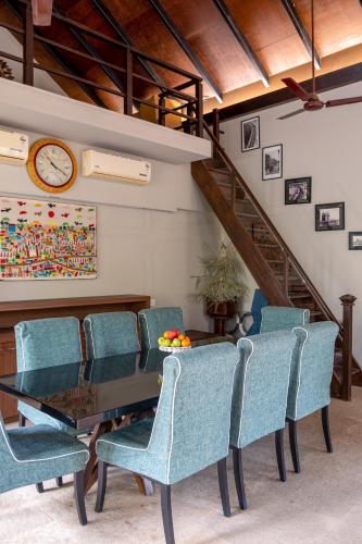 een eetkamer met een tafel, stoelen en een klok bij LohonoStays Villa Amber in Alibaug