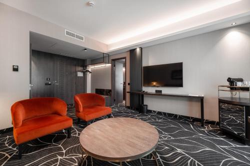a hotel room with two chairs and a table and a tv at Movenpick Hotel Tallinn in Tallinn