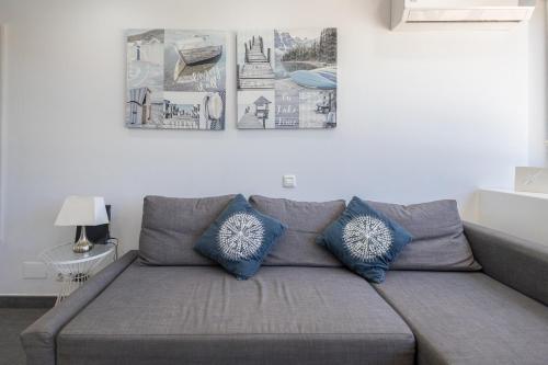 a grey couch with blue pillows in a living room at Complejo Aloe - Pool - close to Maspalomas Beach in San Bartolomé de Tirajana