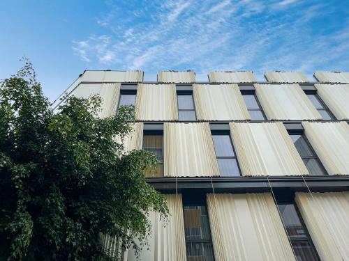 un edificio blanco alto con un árbol delante de él en Hotel MG Poniente, en Las Palmas de Gran Canaria