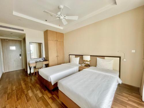 a hotel room with two beds and a desk at Vinholidays Fiesta Phu Quoc in Phu Quoc