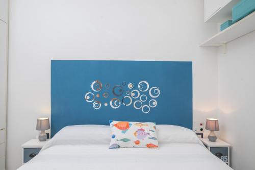 sypialnia z niebieskim zagłówkiem i białym łóżkiem w obiekcie Sardinia Paradise House - Happy Rentals w mieście Marina di Portisco