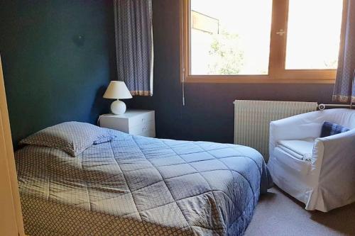 a bedroom with a bed and a chair and a window at L'Ariondaz - Appartement au centre du village, proche des pistes, avec parking in Courchevel
