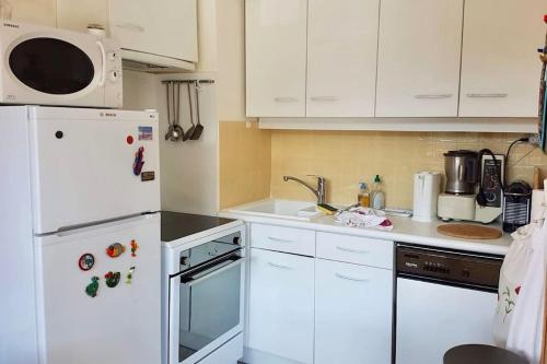 uma cozinha com electrodomésticos brancos e armários brancos em L'Ariondaz - Appartement au centre du village, proche des pistes, avec parking em Courchevel