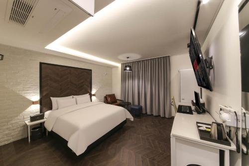 a hotel room with a white bed and a desk at Aden Hotel in Cheonan