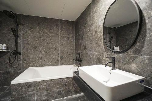 a bathroom with a sink and a tub and a mirror at Aden Hotel in Cheonan