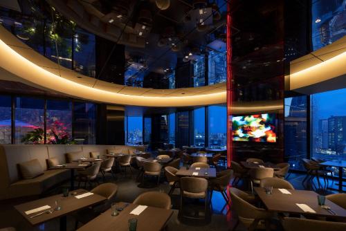 東京にあるHOTEL GROOVE SHINJUKU, A PARKROYAL Hotel の市街の景色を望むレストラン(テーブル、椅子付)