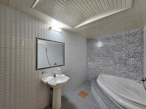 een witte badkamer met een wastafel en een bad bij Hotel G7 Daejeon in Daejeon