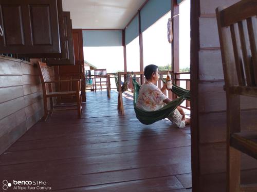 a person sitting in a hammock in a room at Namknong view in Don Det