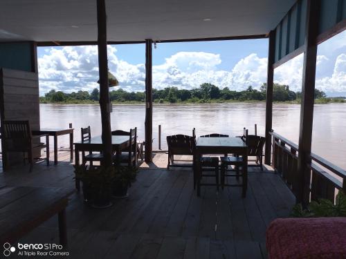 a porch with tables and chairs and a view of a river at Namknong view in Don Det