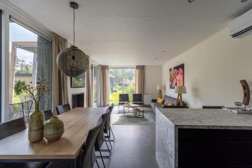 a dining room and living room with a table and chairs at Mooi Twente Lodges - privé Spa en sauna in Markelo