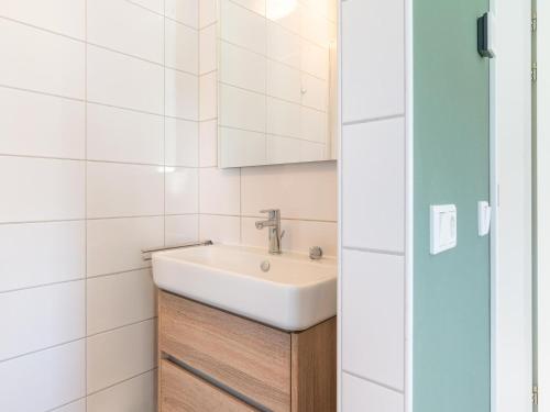 ein Bad mit einem Waschbecken und einem Spiegel in der Unterkunft Attractive holiday home in Scherpenisse with roofed terrace in Scherpenisse