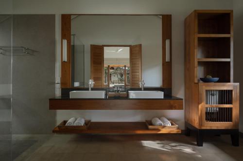 a bathroom with two sinks and a large mirror at Kirana - A Santani Villa in Bentota
