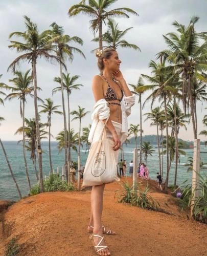a woman in a white dress standing on the beach at Bananas Mirissa in Mirissa