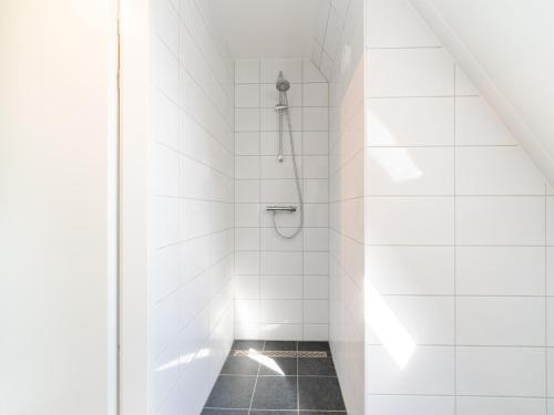y baño de azulejos blancos con ducha. en Modern holiday home in Scherpenisse with infrared sauna, en Scherpenisse