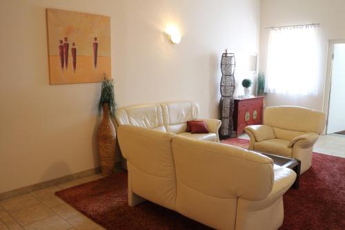 a living room with two white couches and two chairs at Hotel Checkin in Gleisdorf