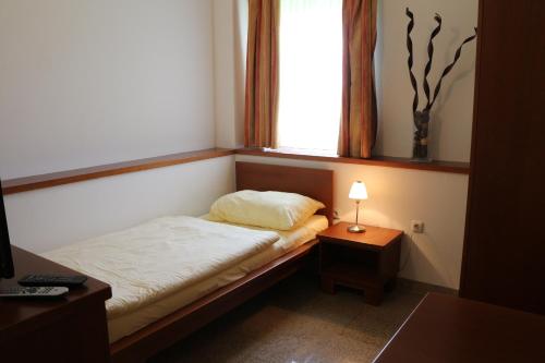a small bedroom with a bed and a window at Hotel Checkin in Gleisdorf