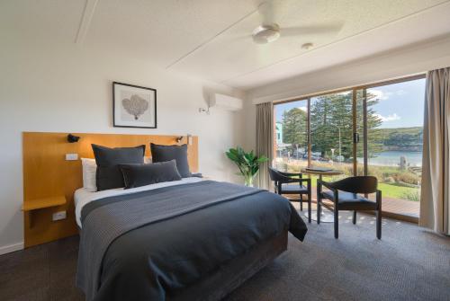 a bedroom with a bed and a table with chairs at Loch Ard Motor Inn in Port Campbell