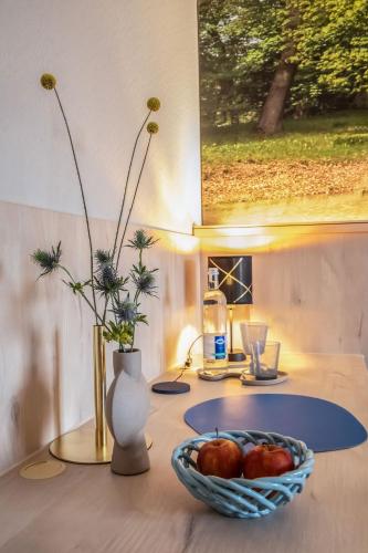 a table with a bowl of fruit and a vase with flowers at Hotel Restaurant Elbebrücke in Oranienbaum-Wörlitz