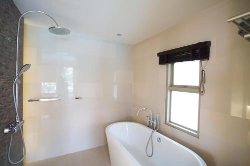 a white bathroom with a tub and a window at Villa Nilaya - Beachfront Villa - Hua Hin in Ban Bo Fai
