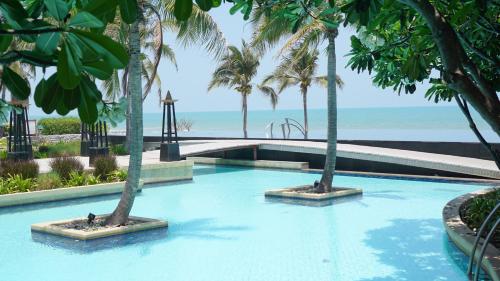 a swimming pool with palm trees and the beach at Villa Nilaya - Beachfront Villa - Hua Hin in Ban Bo Fai