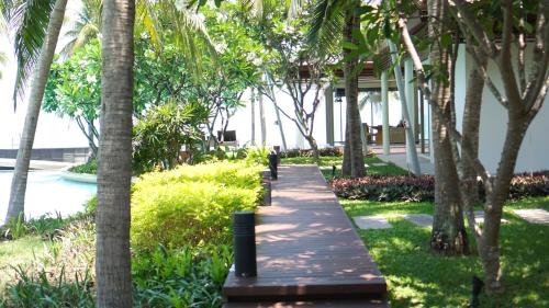 a man walking down a walkway between palm trees at Villa Nilaya - Beachfront Villa - Hua Hin in Ban Bo Fai