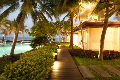 a pathway leading to a resort with palm trees at Villa Nilaya - Beachfront Villa - Hua Hin in Ban Bo Fai