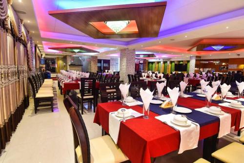 un salón de banquetes con mesas y sillas rojas y azules en Hotel Orion International en Jessore