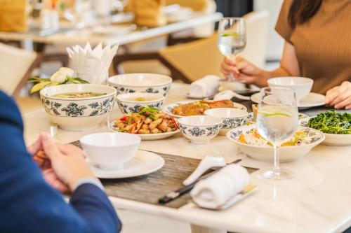people sitting around a table with plates of food at The Five Residences Hanoi in Hanoi
