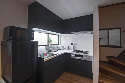 a kitchen with black cabinets and a black refrigerator at 旅time 住吉大社 Sumiyoshi shrine in Osaka