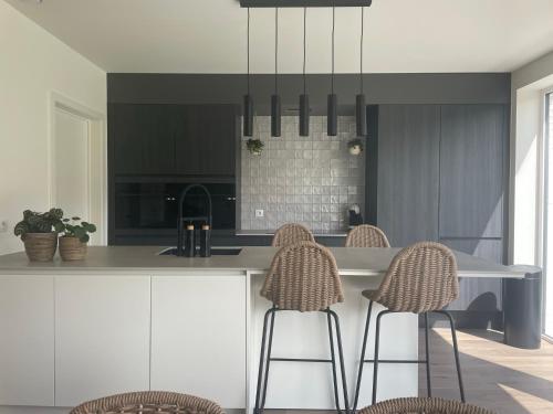 a kitchen with a counter with chairs and a island at Feel@Home Aan Zee in Middelkerke