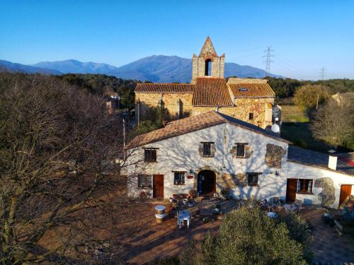 un antico edificio in pietra con una chiesa in montagna di Masia Can Felip B&B a Llinars del Vallès