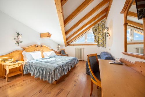 a bedroom with a bed and a desk in a room at Hotel Patrizia Dolomites Glamour in Moena